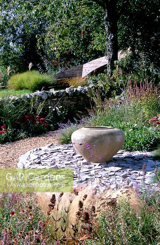 Raised broken slate border with large urn in Devon garden