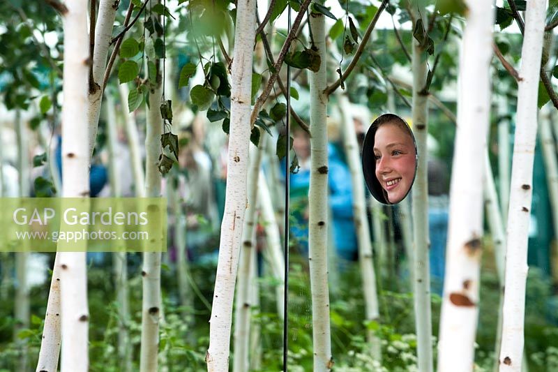 Young girl looking through the mirrored wall into the silver birch 'Forest2' conceptual garden at Hampton Court Flower Show 2008