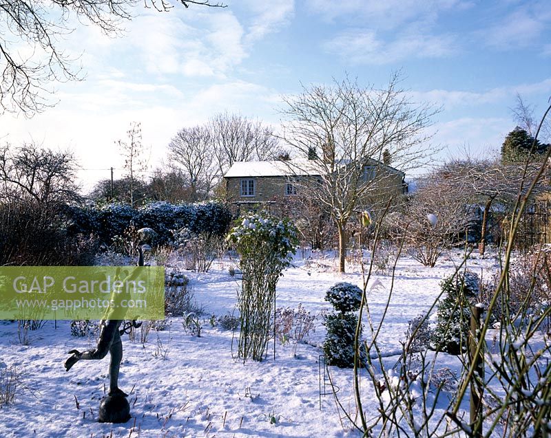 The garden in snow with a statue in the foreground 