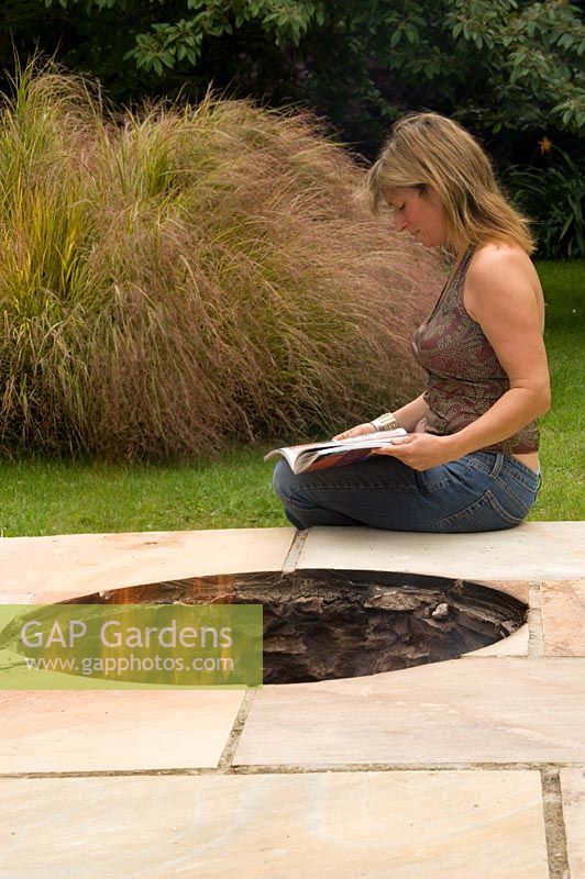 Clare Matthews sits beside the firepit on her patio in her Devon garden