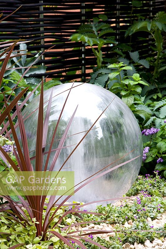 Glass ball water feature with Phormium. Garden - The Way Forward, Designers - Zoe Cain, with Jim Buttress VMH and Jocelyn Armitage, for St Joseph's Hospice and Perennial Gardeners' Royal Benevolent Fund