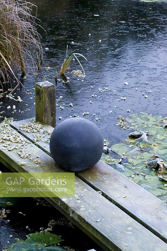 Frozen pond with decorative ball on wooden jetty