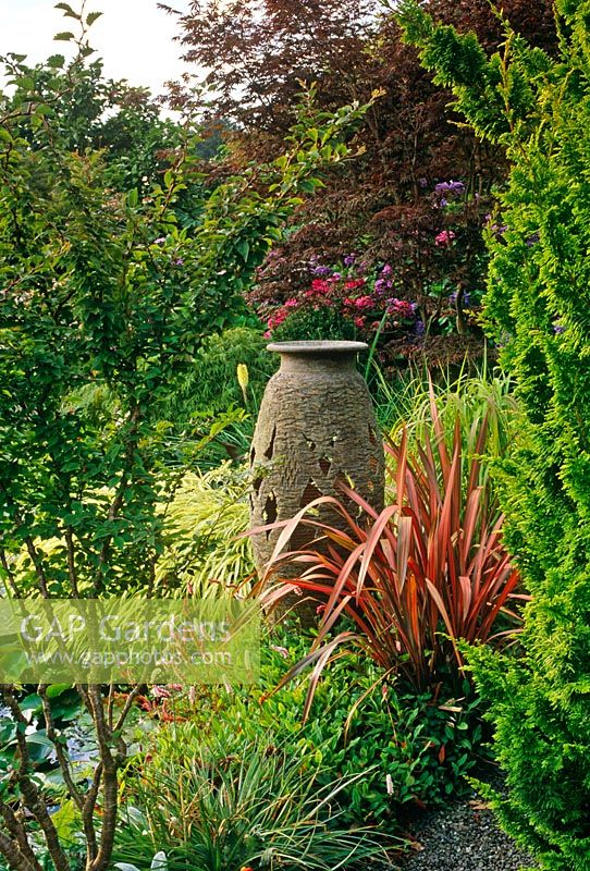 Urn hidden behind Phormium in border with Persicaria affinis and Acer Hakonechloa -Lakemount, Glanmie, Co. Cork, Ireland