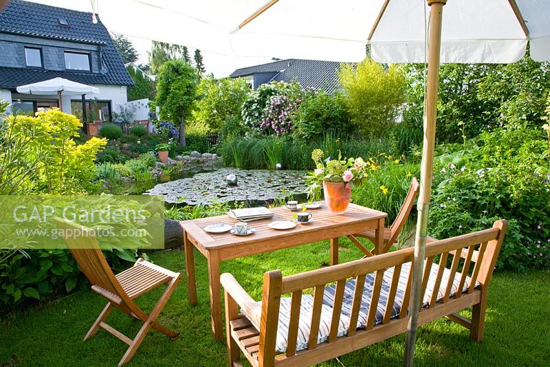 Seating area overlooking large pond in suburban garden