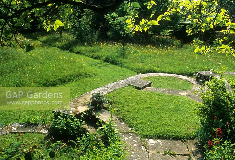 Edwin Lutyens designed stone steps amongst long grass and wild meadow - Great Dixter