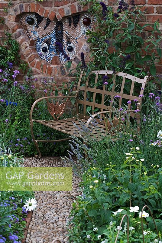 White, blue and purple planting surrounding recessed butterfly shape, in reclaimed brick wall, and metal bench in 'Butterfly Journey' garden, Exhibitor - Chester Zoological Gardens Cheshire's Year of Gardens 08, Tatton Flower Show 2008