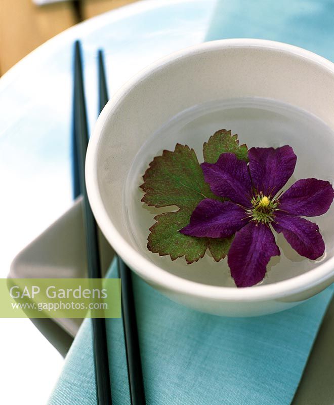 Simple table decoration with Clematis flower and leaf in a water-filled bowl