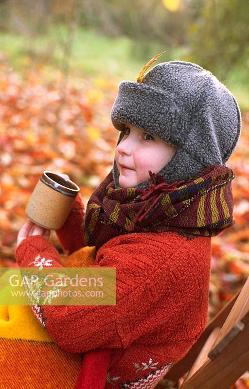 Child wrapped up warm with mug of spiced apple juice