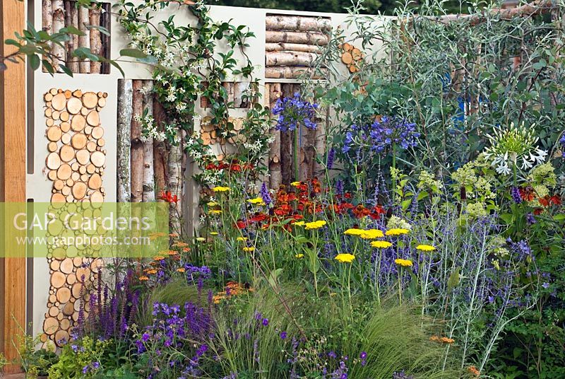 Boundary walls of Courtyard Garden decorated with silver birch logs and discs - RHS Hampton court Flower Show 2008