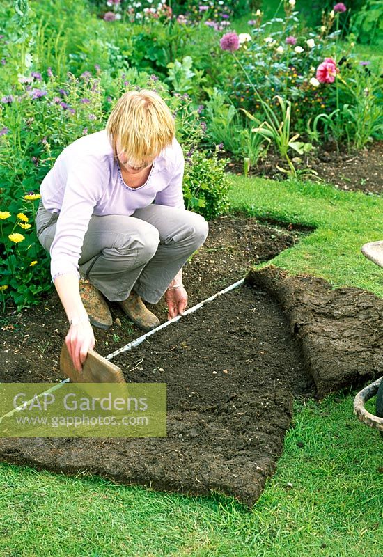 Woman leveling lawn by peeling back turf and adding more soil