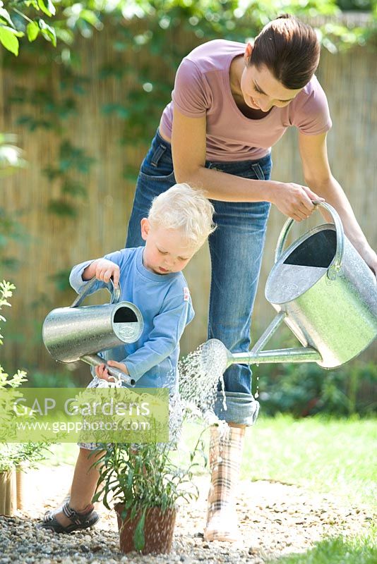 Woman and child watering flowers in container
