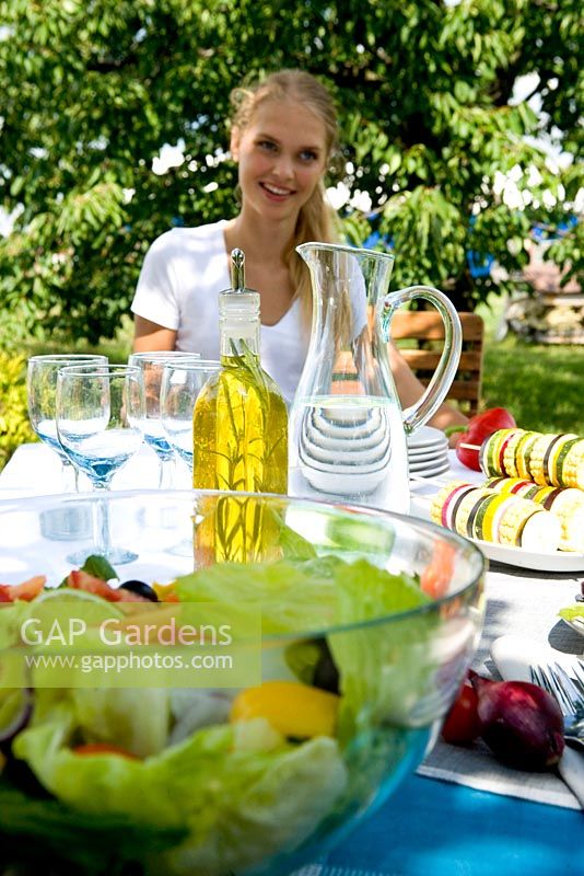 Woman sat beside table of food in garden