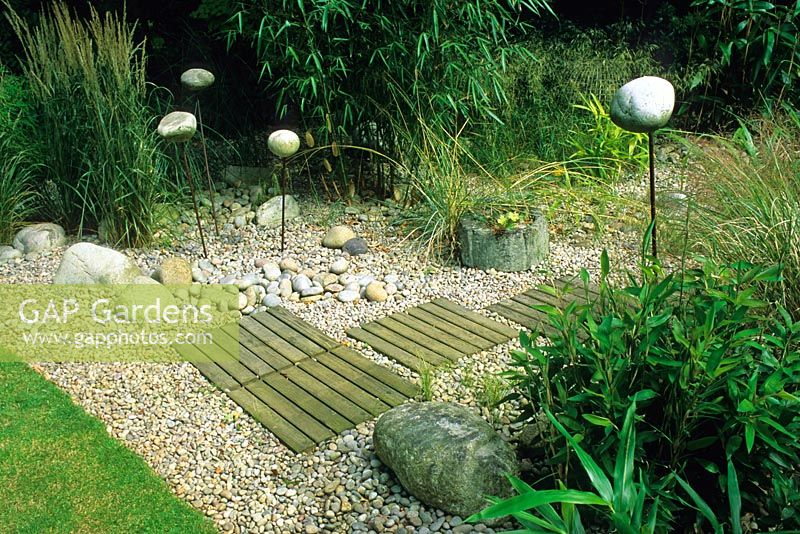 Seaside style garden in August with wooden steps through gravel and ornamental stones. Designed by Alan Titchmarsh at Barleywood, Hampshire.