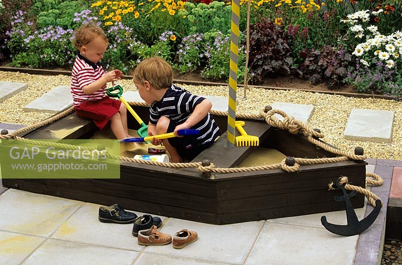 Children playing in a sand pit shaped like a boat