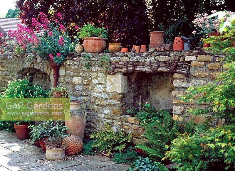 Old stone wall with horseshoes and terracotta pots on top