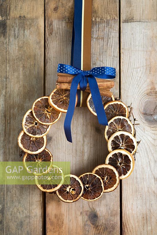 Festive Christmas wreath of dried orange slices and a bundle of cinnamon sticks on wooden background
