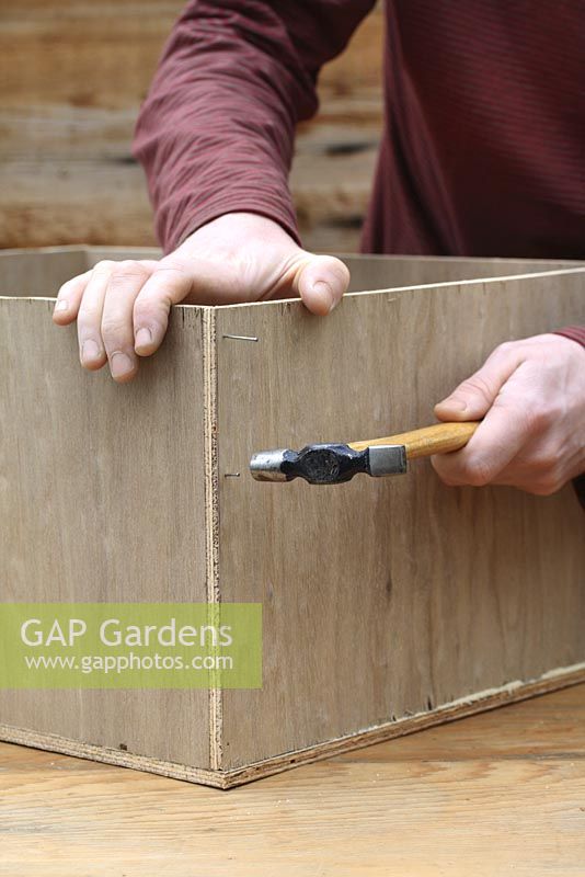 Step by step 2 of making a hedgehog house - Hammering in nails to construct wooden box