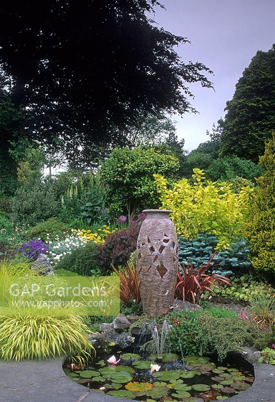 Pond and empty container surrounded by mixed borders - Lakemount, County Cork, Ireland
