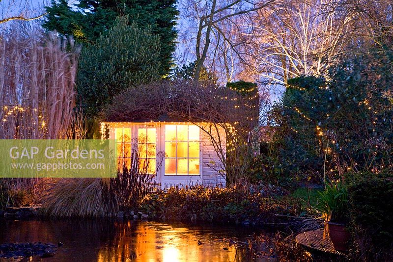 Garden room in winter surrounded by trees with lighting