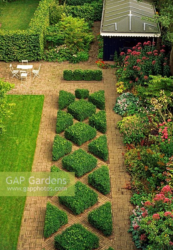 This city garden in the Netherlands is divided into thirds. A geometric treatment of Buxus and brick down the centre is boardered on one side by a lawn and the other by a colourful perennial boarder. 