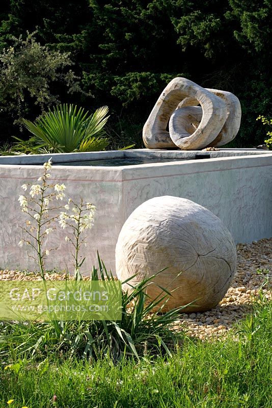 Gravel garden with wooden sculptured ball, Yucca, water feature and twisted sculpture - Marco Nucera's garden, Provence, France