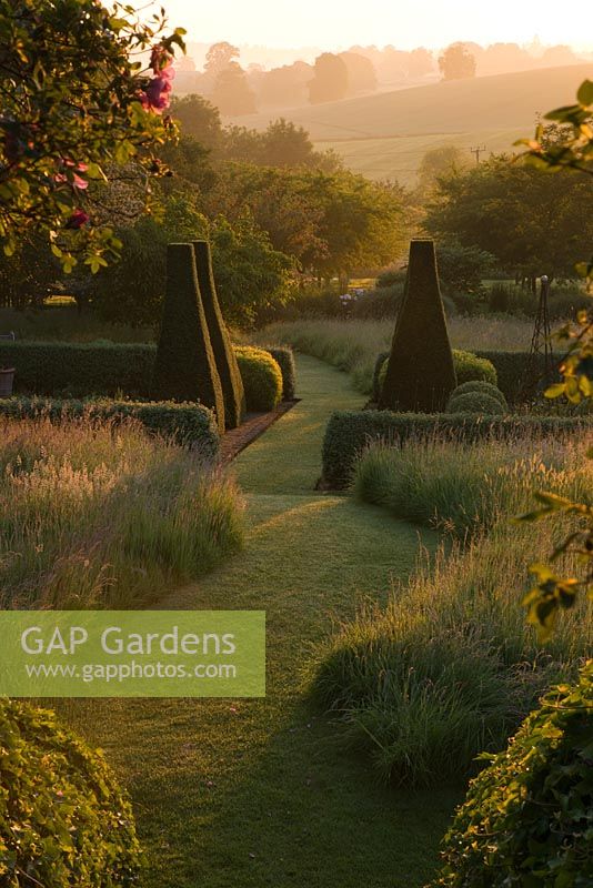 Dawn light hits the parterre framed by rose arbour - Pettifers Garden, Oxfordshire