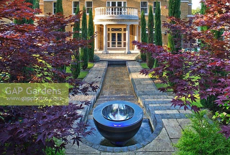 Chalice well water feature with waterfall, rill and house in background
