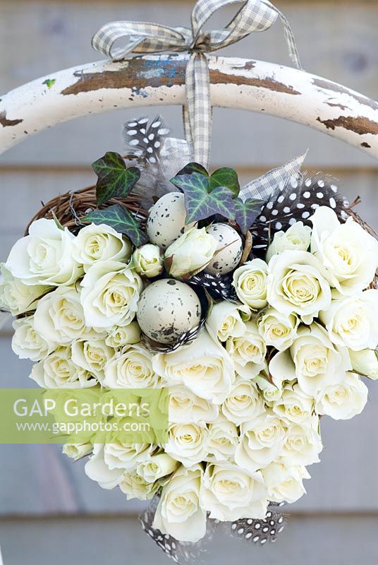 White rose heart wreath with speckled eggs, tied to the back of a rustic chair 