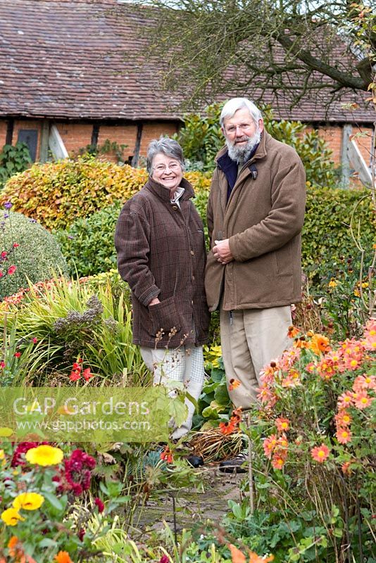 Carol and Malcolm Skinner in their garden in Autumn at Eastgrove Cottage garden, Worcestershire