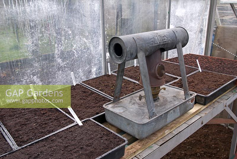 Paraffin heater in greenhouse with newly planted seeds in trays in early Spring