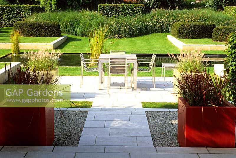 View from the garden room out to the dining terrace, red fibreglass planters with Imperata cylindrica and white planters with Pennisetum - Belgium