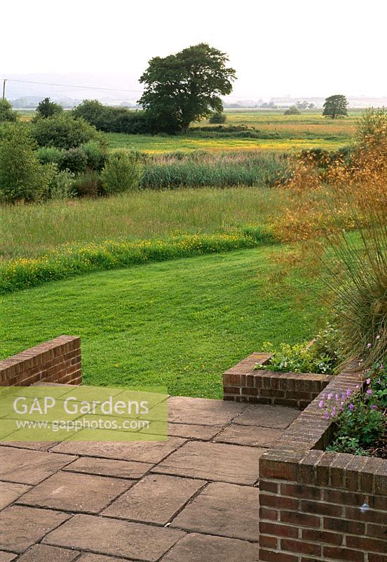 A lower terrace opens to an uninterrupted view across water meadows in this Sussex garden
