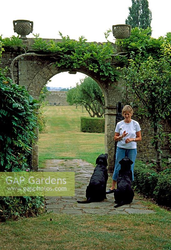 Woman with her two black Labrador dogs - The Monastery Garden