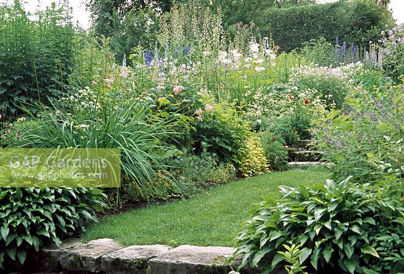 Delphiniums grow in the herbaceous cottage borders - Les Jardins de Quatre-Vents, Quebec