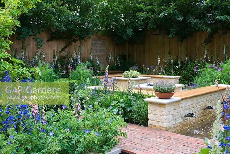 Brick seating area with barbeque, surrounded by plants including Anchusa azurea 'Loddon Royalist', Digitalis x mertonensis, Geranium 'Brookside', Foeniculum vulgare and terracotta planters withThymus vulgare. The QVC Garden, sponsored by QVC - Silver Flora medal winner at RHS Chelsea Flower Show 2009