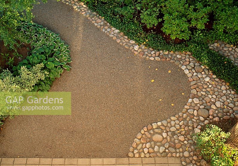 Curving shapes of gravel and laid stones with green borders 