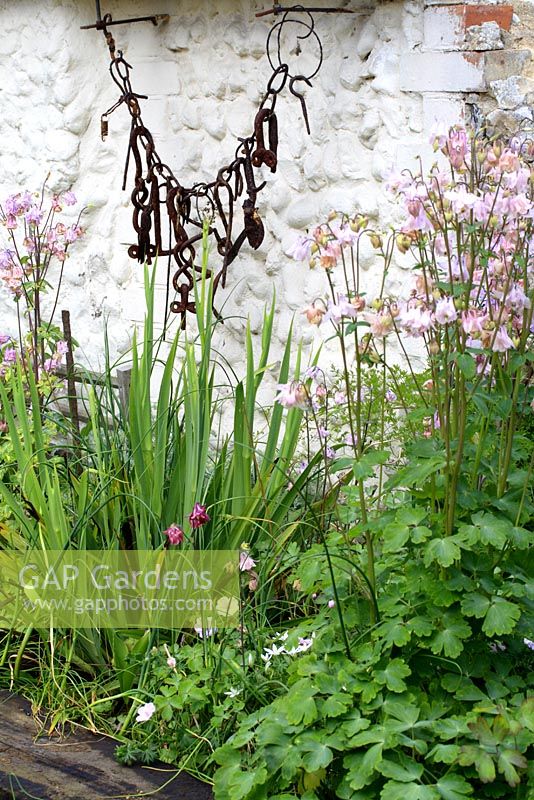 Mixed border with Aquilegia, Iris and hanging recycled metal sculpture