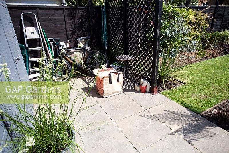 Utility area behind screen in garden with bike and garden waste bag - Small urban garden in London - 
