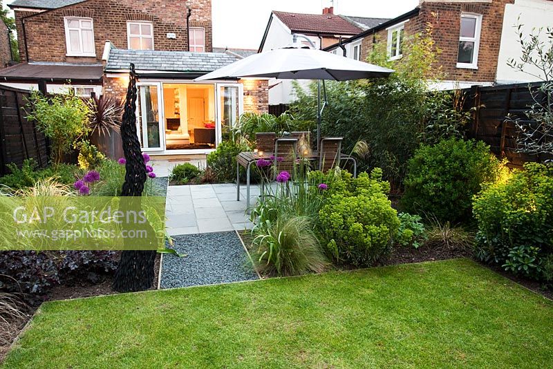 Patioa area with Euphorbia robbiae and Allium 'Purple Sensation' - Small urban garden in London -