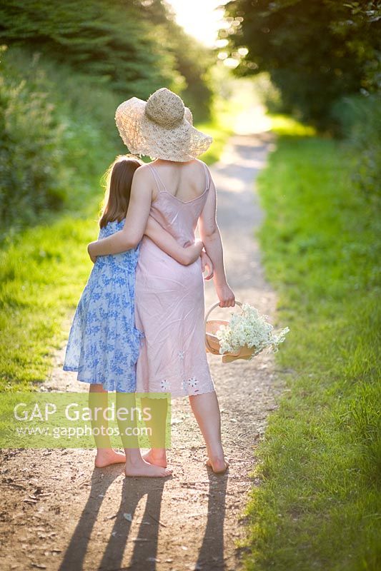Woman holding basket of flowers with girl on path