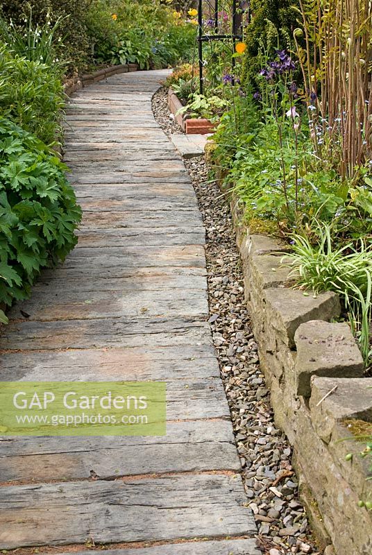 Concrete railway sleeper path edged with pebbles and stone wall at 69 Well Lane, NGS garden, Cheshire