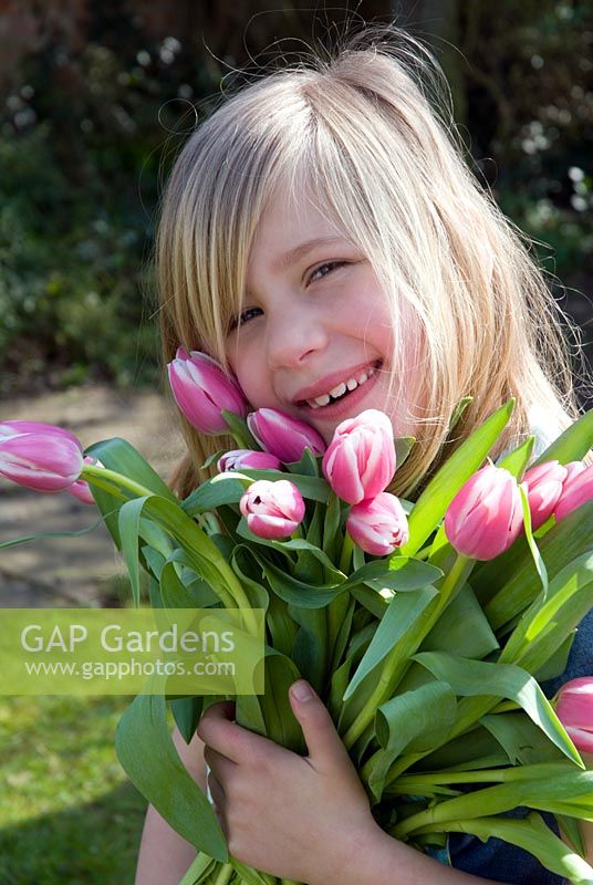 Young girl holding bunch of Tulipa 'Valentine'