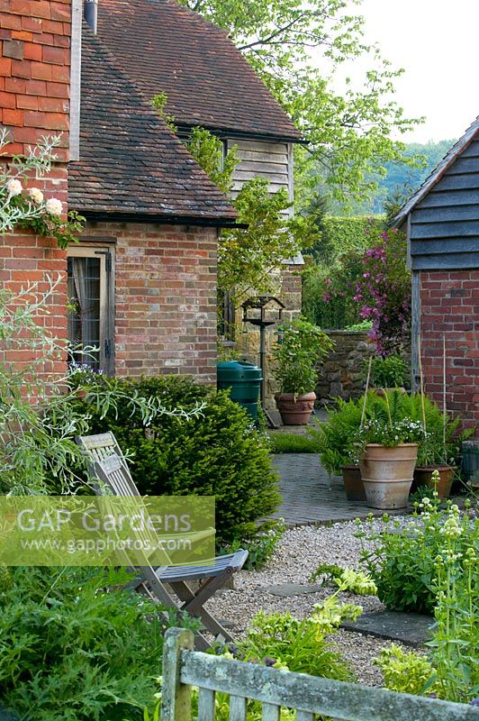 Kitchen patio with gravel, wooden chairs and terracotta pots, Hayes Farmhouse