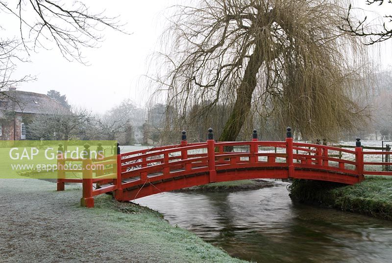 Red Japanese bridge over the river in frost, Heale House Gardens, Wiltshire