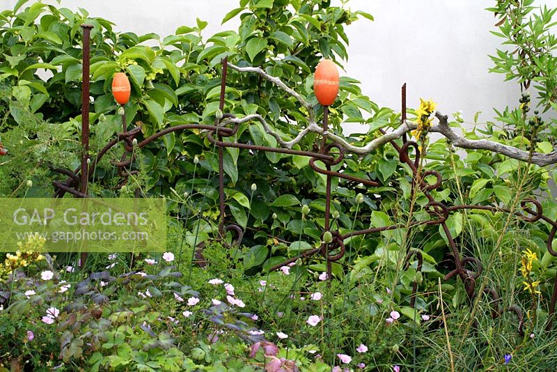 Recycled fencing made from buoys, driftwood and rusty metal in flowerbeds