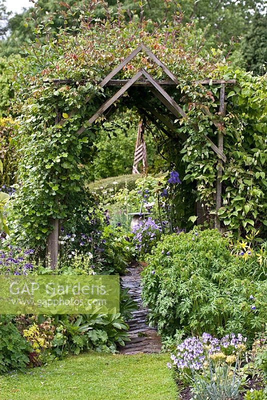 Wooden arch with climbers with Eastgrove Cottage Garden