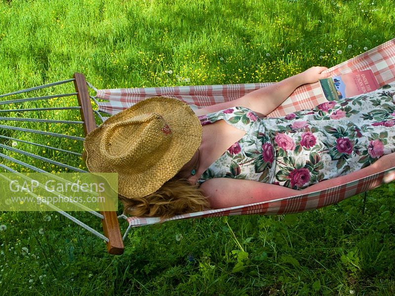 Woman relaxing in hammock with straw hat and flowery dress