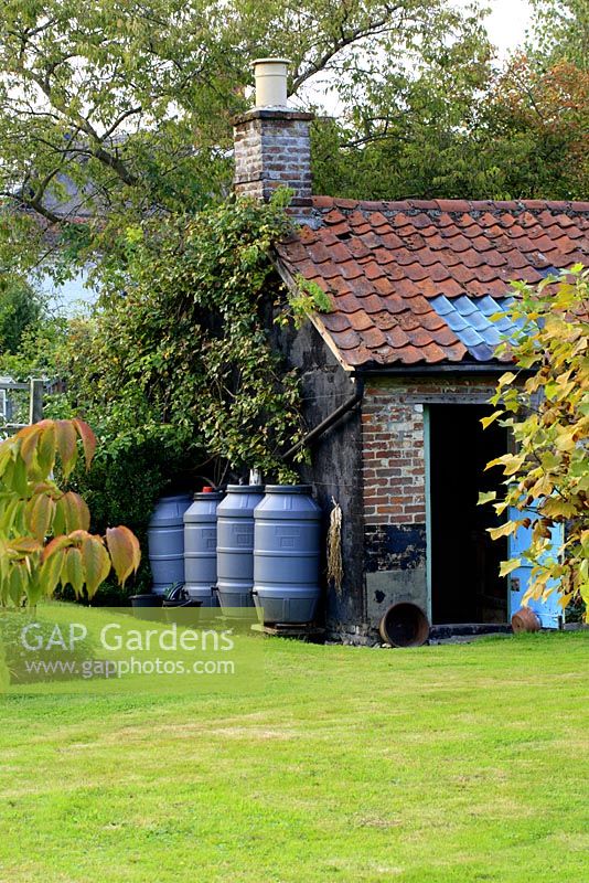 Rustic outbuilding with plastic water butts to collect rainwater