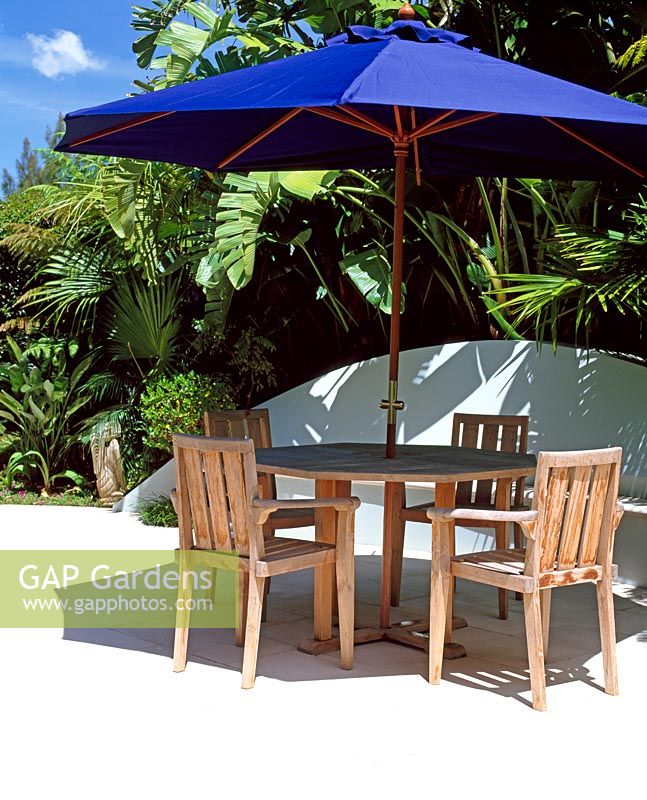 Wooden seating area with blue parasol with tropical planting