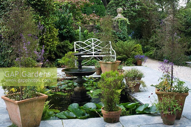 A small pond with water fountain, surrounded by pots in the Northern Summerhouse Garden - The Lost Gardens of Heligan in Cornwall